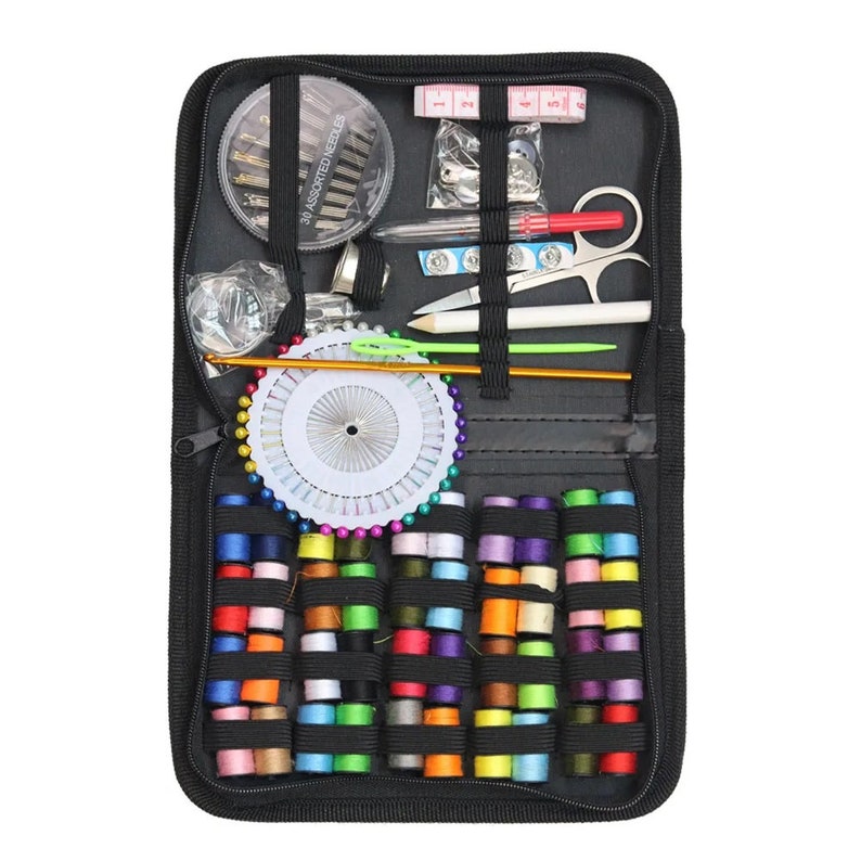 Puede incluir: Una caja negra con cremallera llena de art&iacute;culos de costura, incluyendo carretes de hilo de varios colores, agujas, alfileres, un dedal y unas tijeras peque&ntilde;as.
