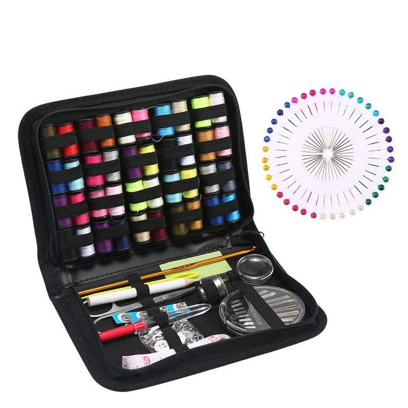 Puede incluir: Una caja negra con cremallera llena de carretes de hilo de colores, agujas de coser, alfileres y otras herramientas de costura. La caja est&aacute; abierta y el contenido es visible.