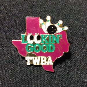 May include: A gold-coloured pin shaped like the state of Texas with the words "Lookin' Good" and "TWBA" in green and white lettering. A bowling ball and pins are depicted in the upper right corner.