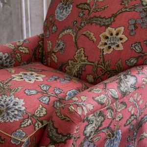 Puede incluir: Un sillón rojo con un patrón floral con acentos azules, verdes y amarillos. La tela es una mezcla de lino con un acabado texturizado.