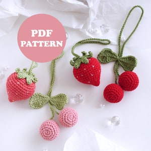 Puede incluir: Un patrón PDF para tejer a crochet un amuleto de fresa y cereza. El amuleto está hecho de hilo rojo y verde y es perfecto para agregar un toque de fantasía a tus proyectos.