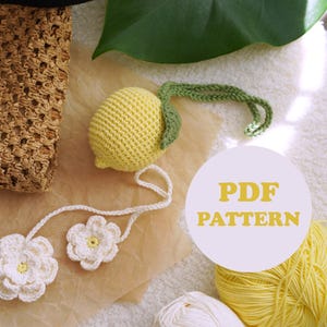 May include: A crocheted lemon with a green stem and a white flower garland. A brown woven bag is on the left. The text "PDF PATTERN" is in a circle in the center of the image. Yellow yarn is in the bottom right.