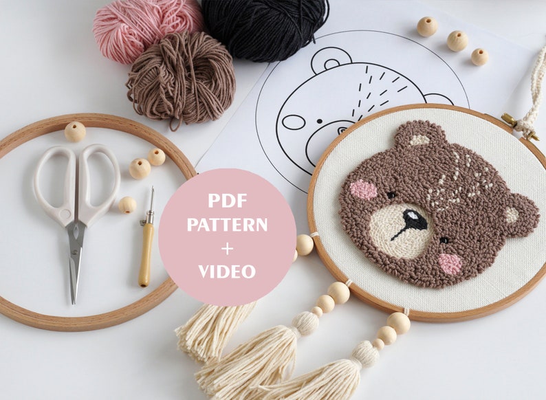May include: A brown bear punch needle embroidery kit with a wooden hoop, yarn, a needle, scissors, and wooden beads. The kit includes a PDF pattern and video instructions.