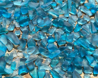May include: A collection of small, translucent blue sea glass pieces. The glass is smooth and has a variety of shapes and sizes.