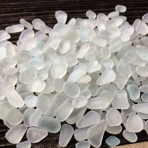 Puede incluir: Un montón de vidrio de mar blanco, liso y esmerilado, con un ligero tono azul. Las piezas de vidrio son de varias formas y tamaños, perfectas para manualidades o decoración.