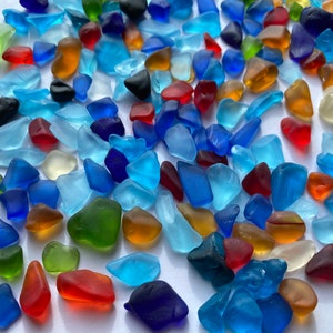 May include: A collection of colourful sea glass pieces in various shapes and sizes. The sea glass is a mix of blue, green, red, brown, and clear glass.