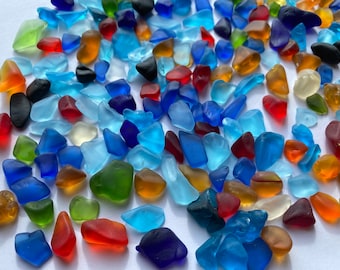May include: A collection of colorful sea glass pieces in various shapes and sizes. The sea glass is a mix of blue, green, red, brown, and clear glass.