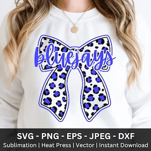 May include: White sweatshirt featuring a large bow design with a blue and white leopard print. The word "Bluejays" is written in blue script across the bow. Below the sweatshirt is the text "SVG - PNG - EPS - JPEG - DXF".