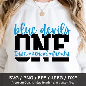 May include: White sweatshirt with the text "blue devils ONE town school family" in blue and black. The design includes hearts and is likely for a school or team. The bottom of the image shows file format options.