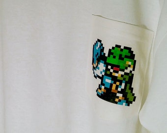 Op de afbeelding: Wit T-shirt met een kleine, gepixelde afbeelding van een videogamepersonage op de linker borstzak.
