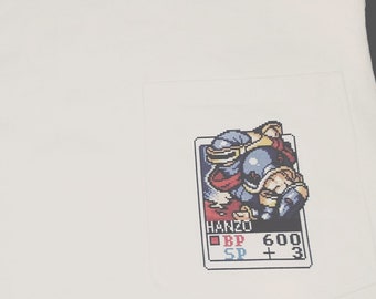 Könnte beinhalten: Weißes T-Shirt mit einer Tasche mit einem pixelartigen Charakterdesign. Das Design enthält den Text "HANZO", "BP 600" und "SP +3".