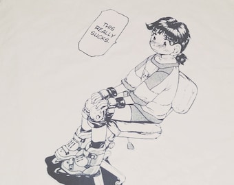 May include: White t-shirt with a black and white illustration of a person sitting on a chair with roller skates. The text "This really sucks." is in a speech bubble above the person.