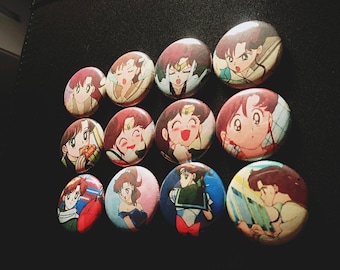 Op de afbeelding: Een verzameling van twaalf ronde, kleurrijke anime-personage-knoppen. De knoppen tonen verschillende personages met verschillende gezichtsuitdrukkingen en poses.