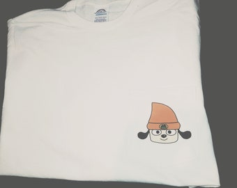 May include: White t-shirt with a cartoon dog wearing an orange hat on the pocket. The dog has black ears and a green hat band.