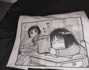Könnte beinhalten: Ein weißes T-Shirt mit einem schwarz-weißen Manga-Grafikdruck von zwei Schülern an Schreibtischen. Ein Schüler hält ein Buch mit der Aufschrift ENGLISH, während der andere mit einem Fragezeichen in einer Sprechblase zuschaut. Japanischer Text.