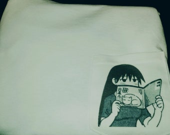 May include: White sweatshirt with a pocket featuring a black and white illustration of a person reading a book with Japanese text that says "猫の日" which translates to "Cat Day".