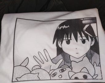 Könnte beinhalten: Ein weißes T-Shirt mit einem schwarz-weißen Grafikdruck im Manga-Stil. Die Illustration zeigt eine Figur mit dunklem Haar, die ihre Hand in Richtung einer Ansammlung kleiner, abgerundeter Kreaturen in einem Greifautomaten ausstreckt.