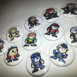 May include: A collection of white, round buttons featuring pixelated character designs in various colors. The characters are in a retro video game style, with details like clothing and hair. The buttons are arranged on a white surface.