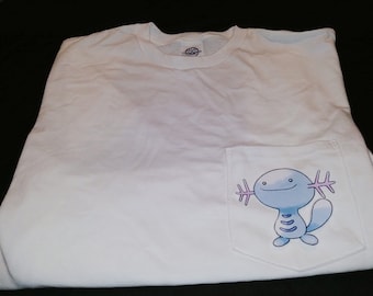 May include: White t-shirt with a blue and pink cartoon axolotl on the pocket.