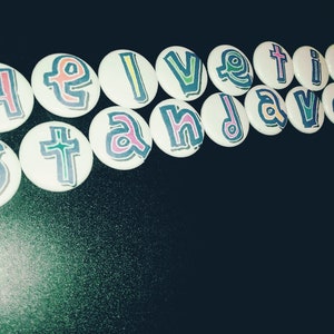 19 one-inch button pins that spell out helvetica standard
