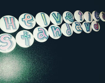 May include: White round buttons with colorful letters spelling out "Helvetica Standard".