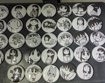 Op de afbeelding: Een verzameling van 36 ronde zwart-witte knoppen met verschillende cartoonfiguren. De knoppen zijn gerangschikt in een rasterpatroon op een zwart oppervlak.