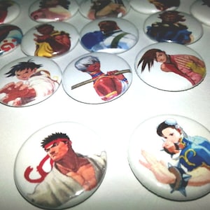 May include: A collection of white, oval-shaped buttons featuring colorful illustrations of characters from a fighting video game. The buttons showcase various characters in action poses, with vibrant colors and detailed artwork.