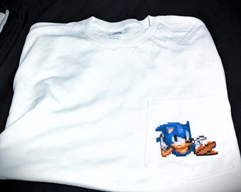 Op de afbeelding: Witte longsleeve t-shirt met een blauwe gepixelde afbeelding van Sonic the Hedgehog in de zak.