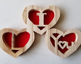 May include: Three wooden hearts with red felt inserts. The hearts are carved with the words "I Love You".