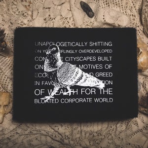 May include: Black patch with white text and a white silhouette of a pigeon. The text reads "Unapologetically shitting on your  iflingly overdeveloped concrete cityscapes built on the motives of eco and greed in favor of wealth for the bloated corporate world."