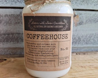 May include: A glass jar candle with a gold lid and twine bow. The label reads Loem Thirteen Candles, COFFEEHOUSE, No. 62, and 14 oz (397 g) with 85-95 hour burn time. The wax is white, and the label describes a blend of coffee, caramel, milk, and vanilla.
