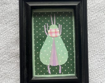 Illustrazione di un insetto verde ritagliato nella carta e incorniciata.