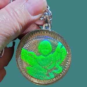 May include: A silver chain with a round pendant featuring a green angel with iridescent wings inside a clear resin dome.
