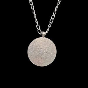 May include: Silver chain necklace with a round silver pendant. The pendant has a textured surface.