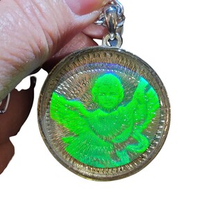 May include: A silver chain with a round pendant featuring a green angel inside a clear resin dome.