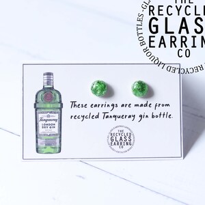 May include: A pair of green glass earrings made from a recycled Tanqueray gin bottle. The earrings are on a white card with a drawing of a Tanqueray gin bottle and the text "These earrings are made from recycled Tanqueray gin bottle."