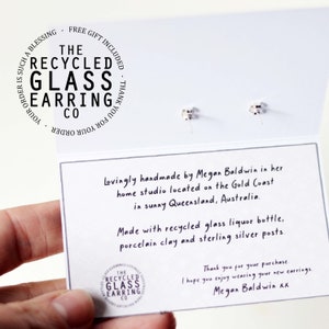 May include: A close-up of a card with the text "The Recycled Glass Earring Co." and the message "Lovingly handmade by Megan Baldwin in her home studio located on the Gold Coast in sunny Queensland, Australia. Made with recycled glass liquor bottle, porcelain clay and sterling silver posts. Thank you for your purchase. I hope you enjoy wearing your new earrings. Megan Baldwin xx"