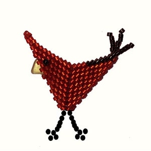 Peut inclure: Figurine d'oiseau en perles rouges et noires. Le corps de l'oiseau est principalement rouge, avec des accents noirs sur les ailes et les pattes. Il a un petit bec doré et des yeux noirs. L'oiseau est fait de petites perles.