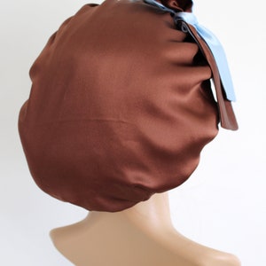 May include: A brown satin sleep cap with a light blue satin bow on top.