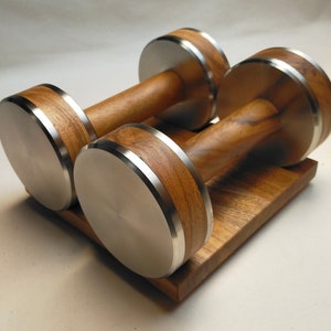 The Coretez dumbbell set, each weighing 6 kg, has smooth-textured wooden handles and stainless steel tips for an elegant look. They come with a matching wooden base for storage. Dumbbells add sophistication to any home gym.