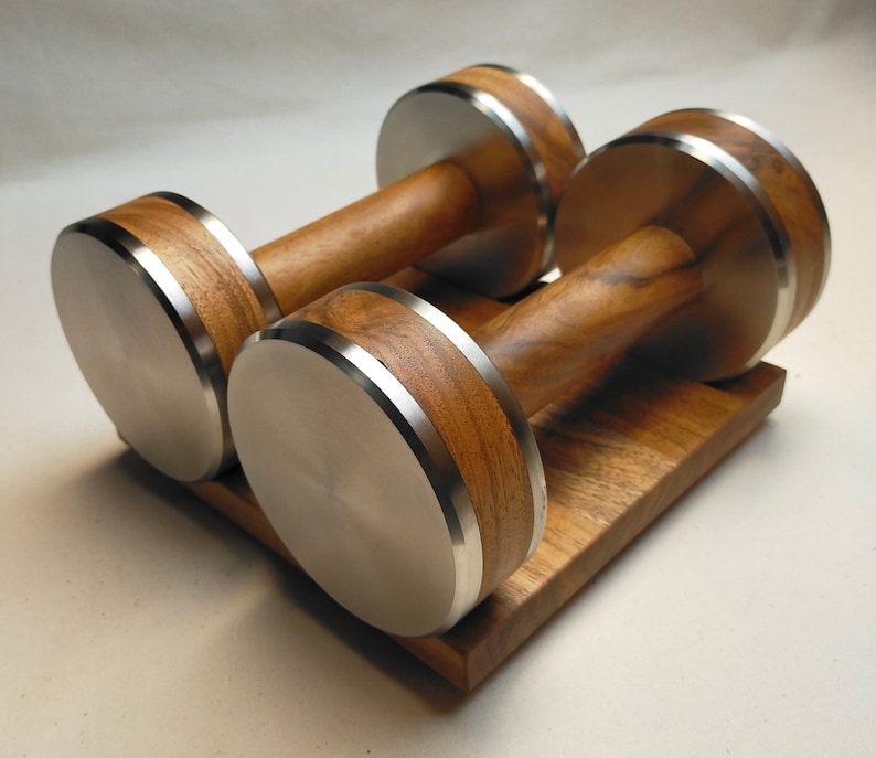 The Coretez dumbbell set, each weighing 6 kg, has smooth-textured wooden handles and stainless steel tips for an elegant look. They come with a matching wooden base for storage. Dumbbells add sophistication to any home gym.