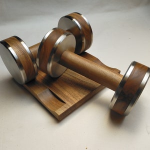 The Coretez dumbbell set, each weighing 6 kg, has smooth-textured wooden handles and stainless steel tips for an elegant look. They come with a matching wooden base for storage. Dumbbells add sophistication to any home gym.