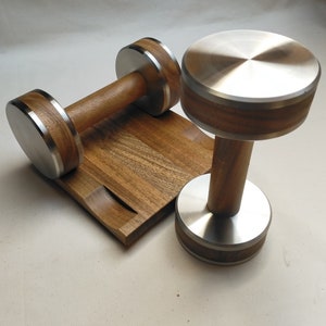 The Coretez dumbbell set, each weighing 6 kg, has smooth-textured wooden handles and stainless steel tips for an elegant look. They come with a matching wooden base for storage. Dumbbells add sophistication to any home gym.