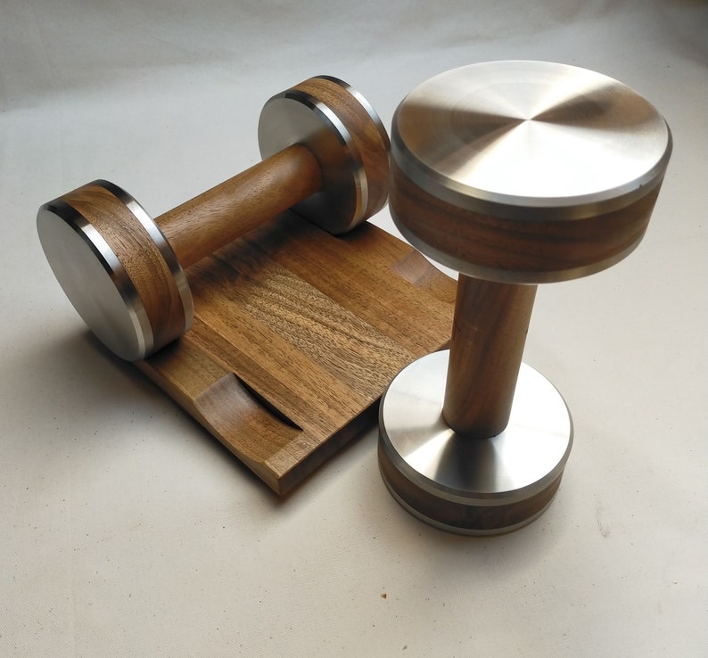 The Coretez dumbbell set, each weighing 6 kg, has smooth-textured wooden handles and stainless steel tips for an elegant look. They come with a matching wooden base for storage. Dumbbells add sophistication to any home gym.