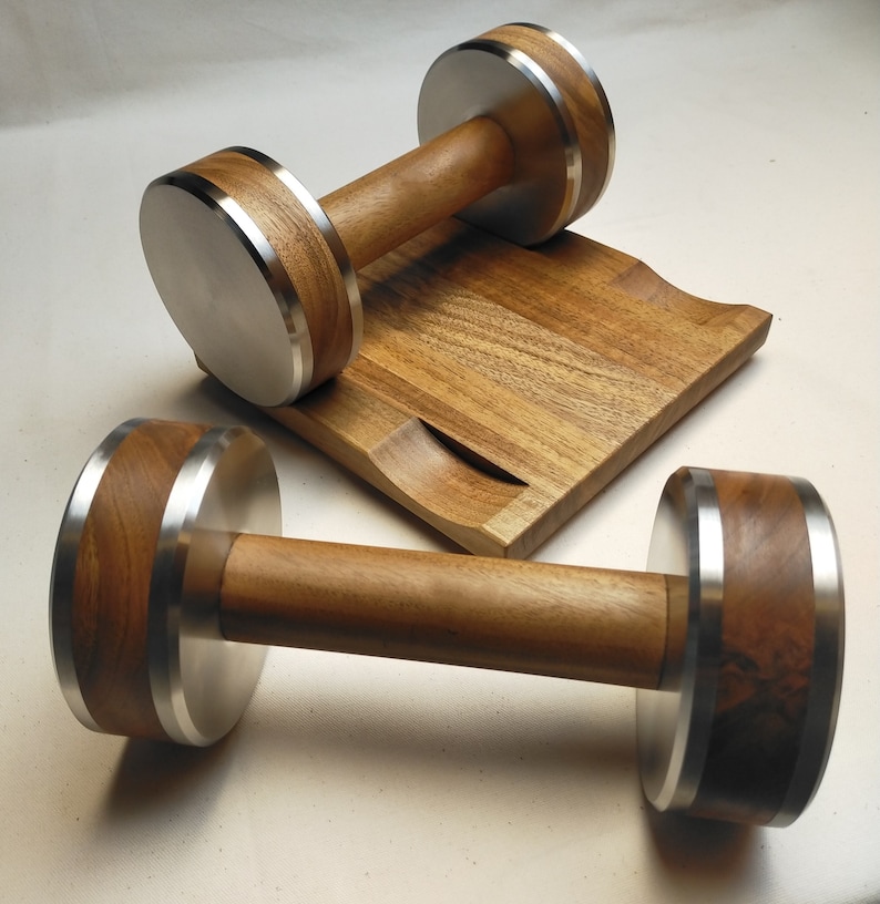 The Coretez dumbbell set, each weighing 6 kg, has smooth-textured wooden handles and stainless steel tips for an elegant look. They come with a matching wooden base for storage. Dumbbells add sophistication to any home gym.