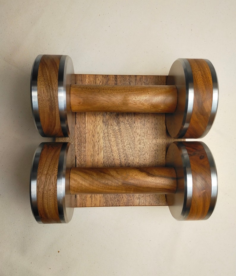 The Coretez dumbbell set, each weighing 6 kg, has smooth-textured wooden handles and stainless steel tips for an elegant look. They come with a matching wooden base for storage. Dumbbells add sophistication to any home gym.