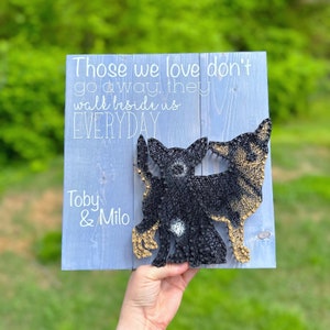 May include: A wooden sign with a quote about love and a string art design of two dogs. The quote reads "Those we love don't go away, they walk beside us EVERYDAY". The names Toby & Milo are written below the quote.