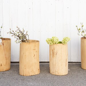 May include: Four wooden planters with different types of white and green flowers. The planters are made from natural wood and have a rustic look.