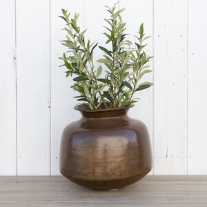 May include: A brown ceramic vase with a wide mouth and a rounded body, filled with green leafy branches.