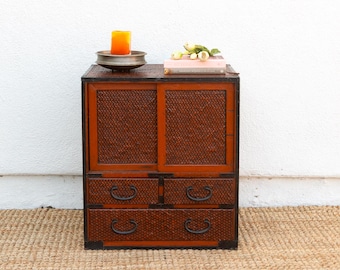 May include: A dark wood cabinet with two doors and three drawers. The cabinet has a woven pattern on the doors and drawers. The cabinet is sitting on a brown rug.